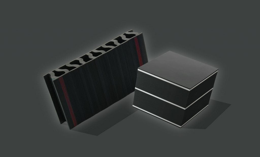 Zwei schwarze rechteckige Objekte mit silbernen Kanten; eines ist eine flache, gerippte Platte mit Rillen zur Schwingungsisolierung, das andere ist ein massiver Würfel, der in drei horizontale Abschnitte unterteilt ist, beide vor einem dunklen Hintergrund.